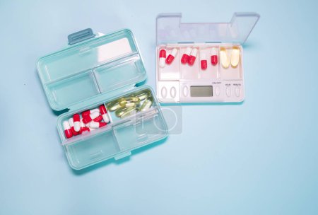 Téléchargez les photos : Plastic boxes with different pills on light blue background - en image libre de droit