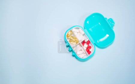 Téléchargez les photos : Boîte en plastique avec différentes pilules sur fond bleu clair - en image libre de droit