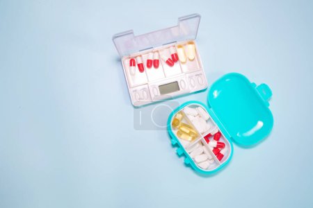 Foto de Plastic boxes with different pills on light blue background - Imagen libre de derechos