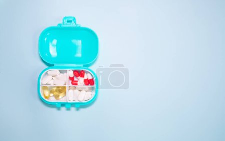Photo for Plastic box with different pills on light blue background - Royalty Free Image