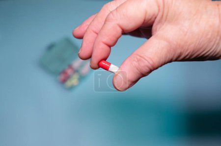 Téléchargez les photos : Hand with pills on blue background. - en image libre de droit