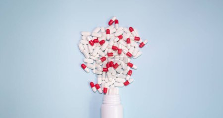 Téléchargez les photos : Medicine bottle and pills spilled on a light blue background. Medicines and prescription pills background - en image libre de droit