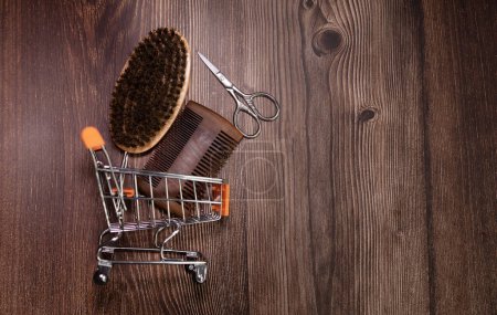 Téléchargez les photos : Old vintage barber shop tools on an old wooden background. Vintage wooden beard combs, beard oils, scissors, electric trimmer, brushes and balm. - en image libre de droit