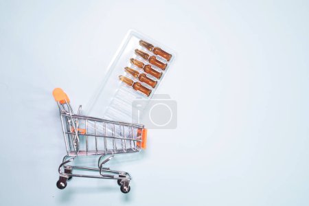 Photo for Shopping cart with medical ampoules on white background - Royalty Free Image