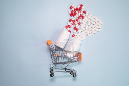 Foto de Shopping cart with pills and tablets on light background. - Imagen libre de derechos