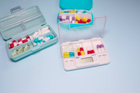 Foto de Plastic boxes with different pills on light blue background, top view. Space for text - Imagen libre de derechos