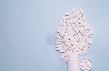 Photo for Medicine bottle and pills spilled on a light blue background. Medicines and prescription pills background - Royalty Free Image
