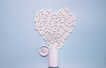 Photo for Medicine bottle and pills spilled on a light blue background. Medicines and prescription pills background - Royalty Free Image