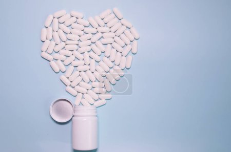 Foto de Medicine bottle and pills spilled on a light blue background. Medicines and prescription pills background - Imagen libre de derechos