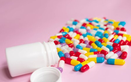 Foto de Medicine bottle and pills spilled on a light pink background. Medicines and prescription pills background - Imagen libre de derechos