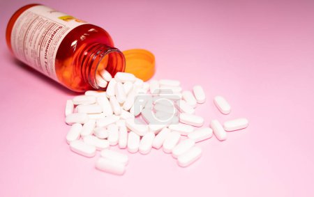 Photo for Medicine bottle and pills spilled on a light pink background. Medicines and prescription pills background - Royalty Free Image