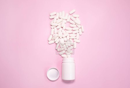 Téléchargez les photos : Flacon de médicament et des pilules renversées sur un fond rose clair. Médicaments et pilules sur ordonnance fond - en image libre de droit
