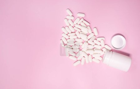 Foto de Frasco de medicamentos y pastillas derramadas sobre un fondo rosa claro. Medicamentos y pastillas de prescripción antecedentes - Imagen libre de derechos