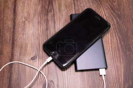 Téléchargez les photos : Powerbank charge smartphone sur fond en bois. - en image libre de droit