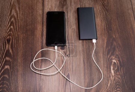 Foto de PowerBank carga smartphone sobre fondo de madera. - Imagen libre de derechos