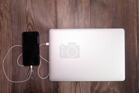 Photo for Plug in USB cord, cable charger, charging, charged and data transfer of the mobile phone, smartphone with a laptop - Royalty Free Image