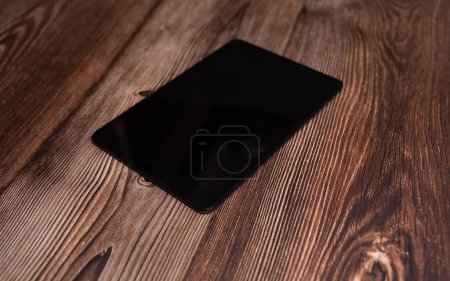 Foto de Tableta digital con pantalla en blanco sobre fondo de madera. - Imagen libre de derechos