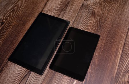 Foto de Tabletas digitales ordenadores con pantallas en blanco sobre fondo de madera. - Imagen libre de derechos
