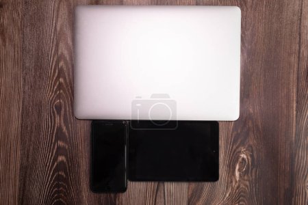 Foto de Dispositivos con pantallas en blanco sobre fondo de madera - Imagen libre de derechos