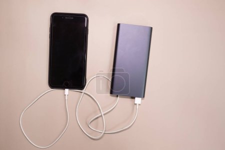 Photo for Powerbank charging smartphone on beige background. - Royalty Free Image