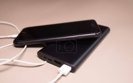 Téléchargez les photos : Powerbank charge smartphone sur fond beige. - en image libre de droit