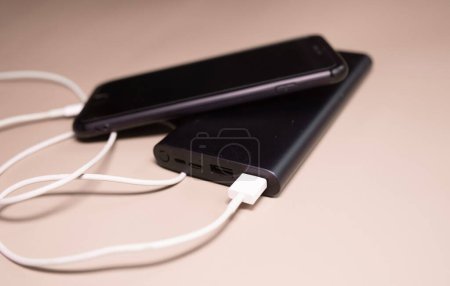Téléchargez les photos : Powerbank charge smartphone sur fond beige. - en image libre de droit