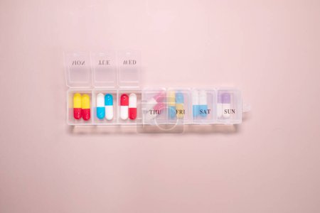 Foto de Caja de plástico con diferentes píldoras sobre fondo beige. Espacio para texto - Imagen libre de derechos