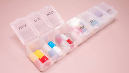 Téléchargez les photos : Boîte en plastique avec différentes pilules sur fond beige. Espace pour le texte - en image libre de droit