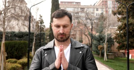Téléchargez les photos : Jeune homme caucasien faisant un geste namaste à l'extérieur - en image libre de droit