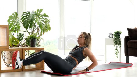 Photo for Strong Athletic Fitness Girl in Sportswear Doing Exercises in Bright Living Room. - Royalty Free Image
