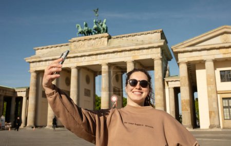 Foto de Turista visitando la Puerta de Brandenburgo y tomando fotos con smartphone en Berlín, Alemania - Imagen libre de derechos