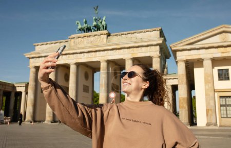 Foto de Turista visitando la Puerta de Brandenburgo y tomando fotos con smartphone en Berlín, Alemania - Imagen libre de derechos