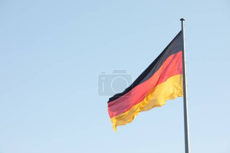 Photo for Germany flag waving in the wind close-up against a blue sky. - Royalty Free Image