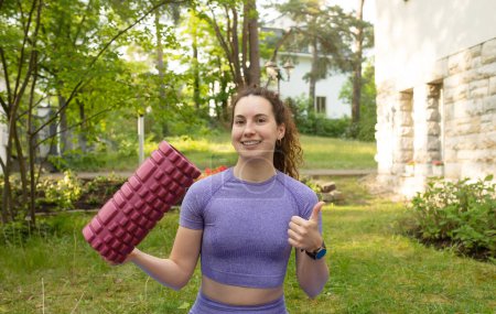 Photo for Beautiful smiling young fit woman holding yoga roller outdoor - Royalty Free Image