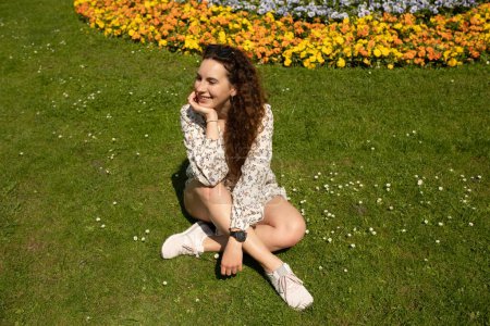 Téléchargez les photos : Portrait d'une belle femme souriante assise sur une herbe en plein air - en image libre de droit