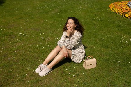 Foto de Retrato de una hermosa mujer sonriente sentada en una hierba al aire libre - Imagen libre de derechos