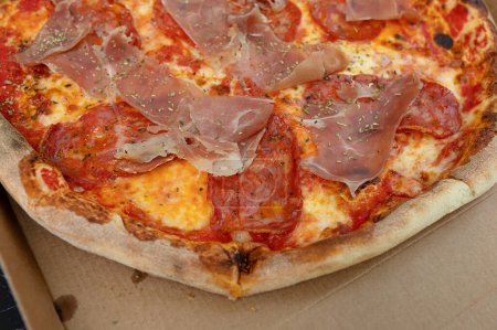 Foto de Pizza con queso Mozzarella, jamón, pimienta, carne, salsa de tomate, especias y rúcula fresca. Fondo de pizza italiana. - Imagen libre de derechos