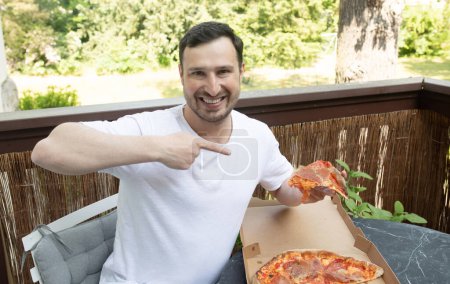 Téléchargez les photos : Beau jeune homme pointant vers la boîte de pizza savoureuse. - en image libre de droit