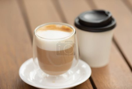 Foto de Dos tazas de café sobre fondo rústico. Taza de papel de café y taza de vidrio. Café para llevar. - Imagen libre de derechos