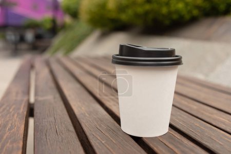 Téléchargez les photos : Fermer tasse de café à emporter sur la table sur fond bokeh. - en image libre de droit