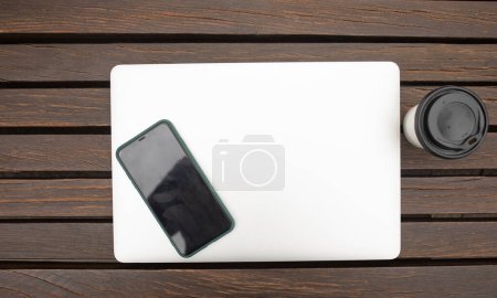 Foto de Ordenador portátil, teléfono inteligente y café sobre fondo de madera, vista superior - Imagen libre de derechos