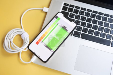 Photo for Power battery with mobile phone and laptop on yellow background - Royalty Free Image