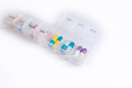 Téléchargez les photos : Récipient avec des pilules colorées pour le traitement médical sur fond blanc - en image libre de droit