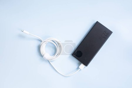 Photo for Close-up view of black powerbank with cable on blue background. Close-up view with copy space. - Royalty Free Image