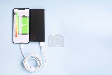 Téléchargez les photos : Charge smartphone avec powerbank noir sur fond bleu - en image libre de droit
