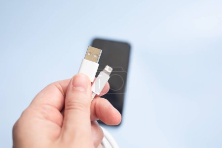 Téléchargez les photos : Homme tenant câble USB et smartphone sur fond de lumière - en image libre de droit