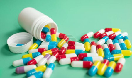 Photo for Colorful pills and tablets and container on green background - Royalty Free Image