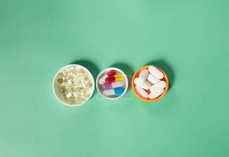 Téléchargez les photos : Vue rapprochée de capsules médicales colorées sur fond vert. - en image libre de droit