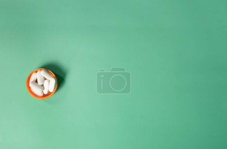 Photo for White pills in bottle cap on green. Vitamins and healthy lifestyle. Background about health and medicine with copy space. - Royalty Free Image