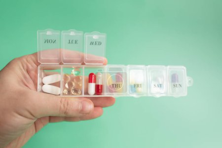 Téléchargez les photos : Gros plan main tenant des pilules de médecine sur fond vert. - en image libre de droit